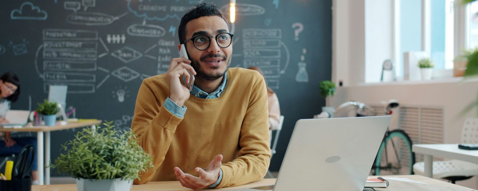 Man on a phone call at a desk with a laptop