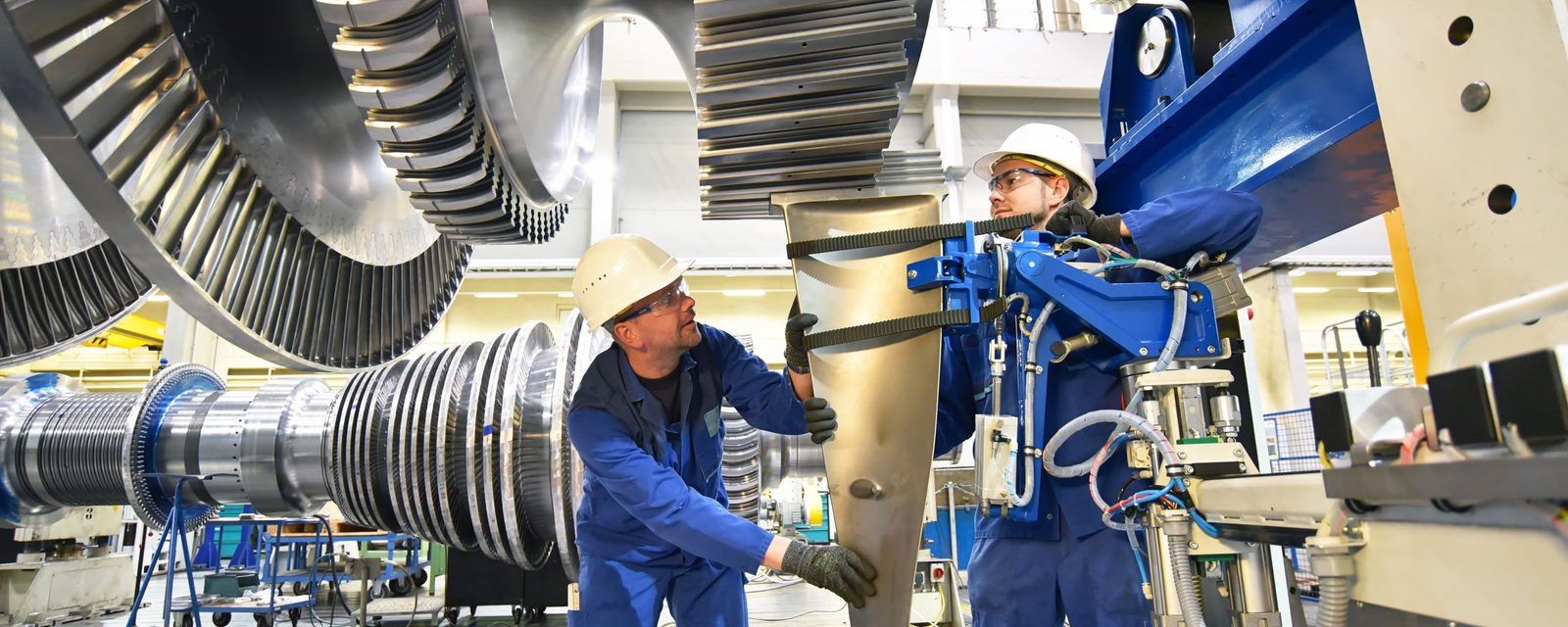 Two technicians in hard hats working on a large turbine