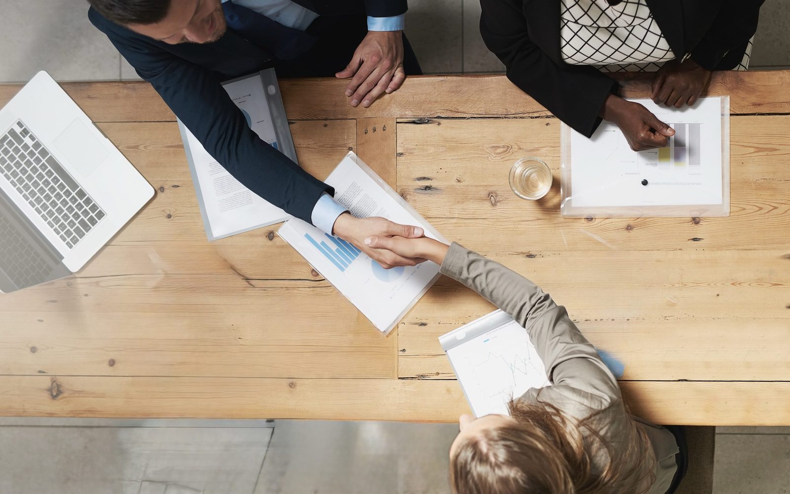 Overhead view of two people shaking hands across a meeting table